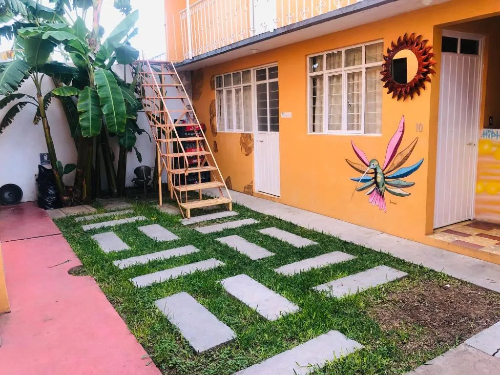 Patio con pasto, escalera de madera y mural de colibrí